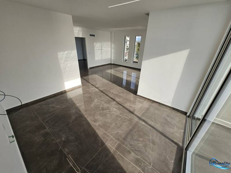  Albánsko, Sarandë – luxusné novostavby apartmánov v prvom rade - Interiér rekreačného apartmánu s veľkými oknami a lesklou dlažbou.