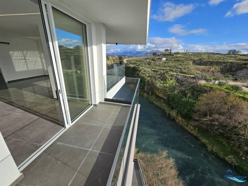 Albánsko, Sarandë – luxusné novostavby apartmánov v prvom rade - Balkón rekreačného apartmánu v Sarandë s výhľadom na rieku a krajinu v pozadí.