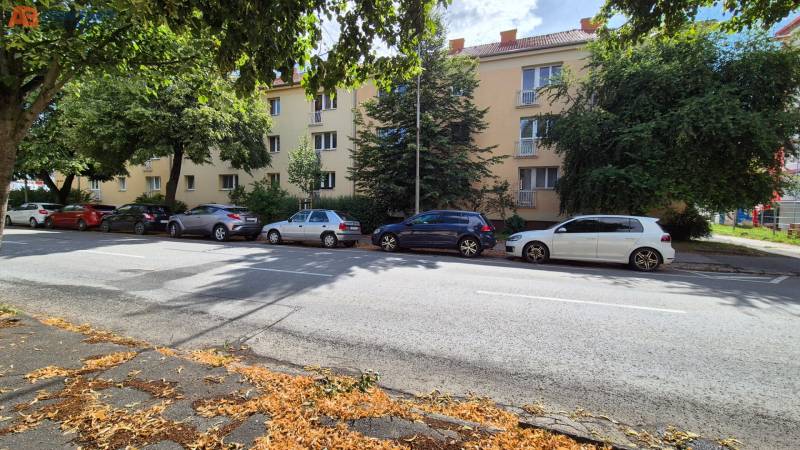 Tehlový 3-izbový byt v pôvodnom stave Pod Párovcami  - Budova na ulici Pod Párovcami v Piešťanoch, obklopená stromami a zaparkovanými autami.