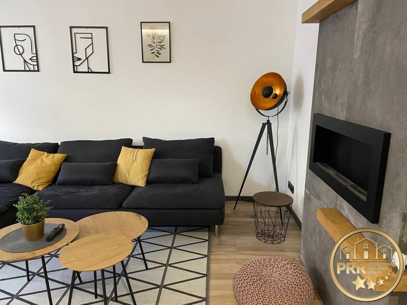 Na predaj krásny komplet prerobený, moderne zariadený 3-izb. byt v BnB - Obývacia izba v 3-izbovom byte s čiernou sedačkou a dekoratívnym osvetlením.
