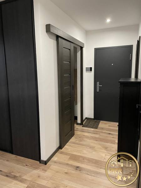 Na predaj krásny komplet prerobený, moderne zariadený 3-izb. byt v BnB - Vstupná chodba do 3-izbového bytu s drevenými podlahami a tmavými posuvnými dverami.