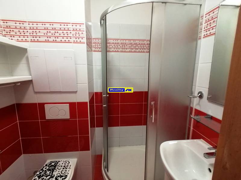 2 izbový byt na prenájom Vrútky, balkón - Kúpeľňa v 2-izbovom byte s červenými obkladmi, sprchovým kútom a umývadlom.