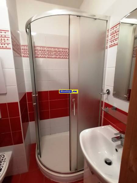 2 izbový byt na prenájom Vrútky, balkón - Kúpeľňa so sprchovacím kútom a umývadlom v 2-izbovom byte s červenými obkladmi.