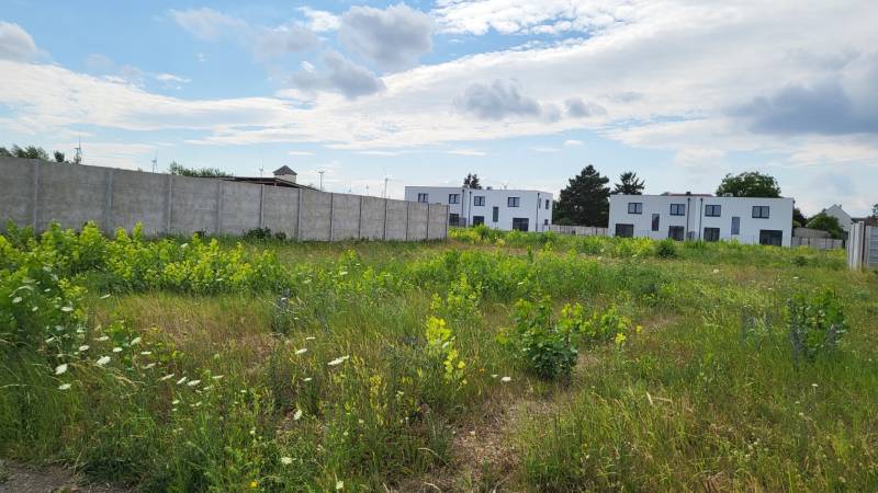Stavebný pozemok 545 m2, Potzneusiedl - Pozemky - bývanie v Potzneusiedli obkolesené zeleňou a modernými budovami v pozadí.