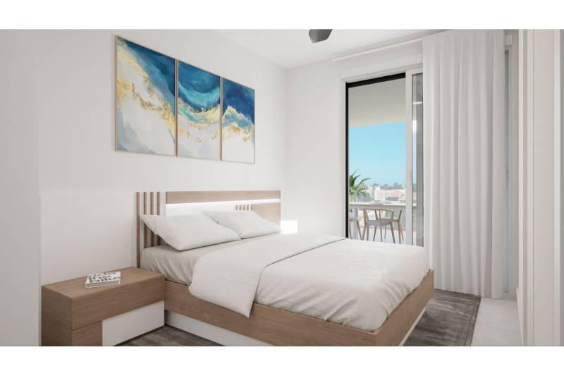 LOS ALCÁZARES -rekreačné apartmány s turistickou licenciou na prenájom - Rekreačný apartmán s manželskou posteľou, nočným stolíkom, balkónovými dverami a obrazom na stene.