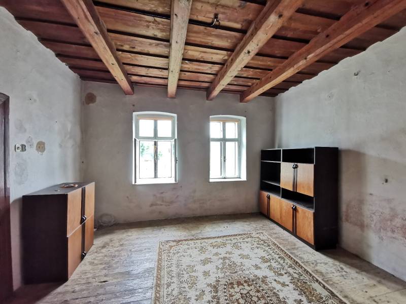 PREDAJ-vidiecky dom s veľkým pozemkom pod lesom, Nitr.Sučany, okr.PD - Izba v rodinnom dome s dreveným stropom, okná, skrinky, koberec na podlahe.