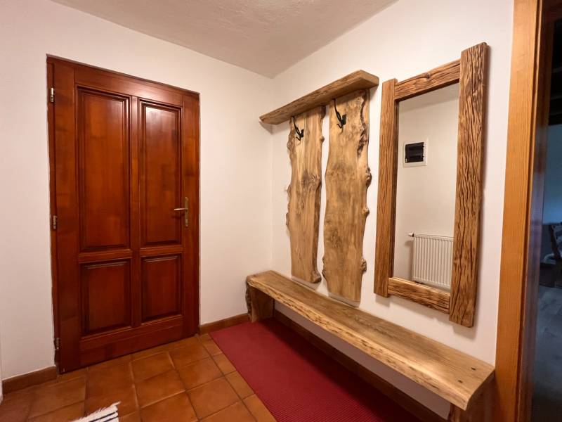Na Predaj: Rozprávkový Rodinný Dom vo Vagrinci, Len Kúsok od Svidníka  - Drevená lavička a vešiak s prírodným zrkadlom v interiéri rodinného domu.