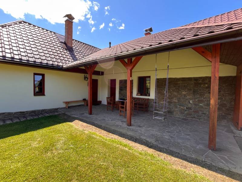 Na Predaj: Rozprávkový Rodinný Dom vo Vagrinci, Len Kúsok od Svidníka  - Záhrada rodinného domu s terasou, stoličkami a hojdačkou v meste Vagrinec na ulici Vagrinec.