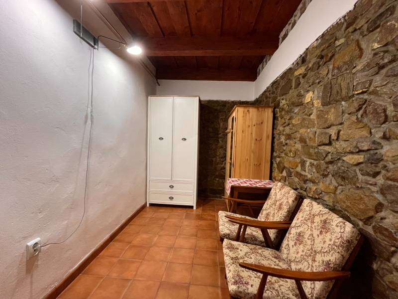 Na Predaj: Rozprávkový Rodinný Dom vo Vagrinci, Len Kúsok od Svidníka  - Kamenná stena, dve kreslá, biely a drevený šatník, keramická podlaha.