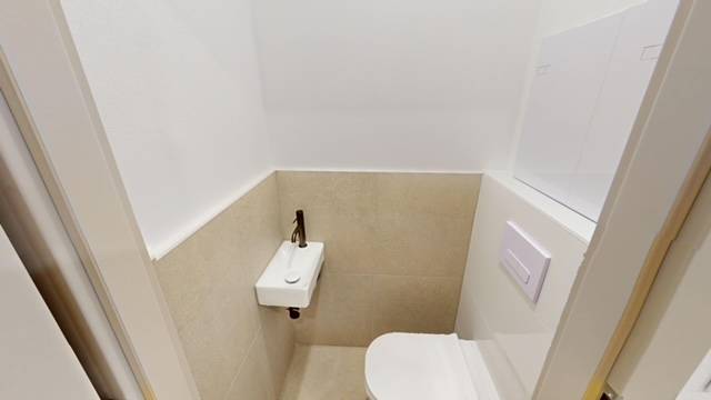 PRENÁJOM - Priestranný moderný 2 izbový byt s 2 balkónmi - Kompaktné WC s umývadlom v 2-izbovom byte, béžové dlaždice a biela stena.