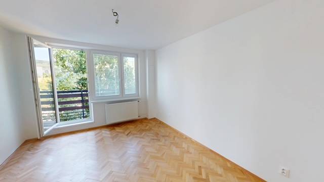 PRENÁJOM - Priestranný moderný 2 izbový byt s 2 balkónmi - Priestranná izba v 2-izbovom byte s drevenou podlahou a veľkým oknom na balkón.