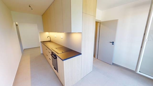 PRENÁJOM - Priestranný moderný 2 izbový byt s 2 balkónmi - Kuchyňa v 2-izbovom byte s drevenými skrinkami, čiernou pracovnou doskou a drezom.