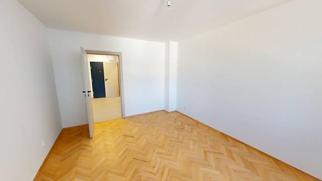 PRENÁJOM - Priestranný moderný 2 izbový byt s 2 balkónmi - Izba v 2-izbovom byte s parketovou podlahou a bielymi stenami.