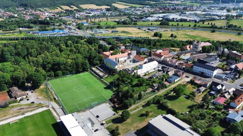 SLOVREAL predaj pozemku Žiar nad Hronom - Letecký pohľad na Žiar nad Hronom, obklopený zeleňou, s futbalovým ihriskom neďaleko centra. Pozemky - bývanie.