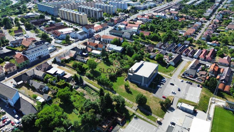 SLOVREAL predaj pozemku Žiar nad Hronom - Letecký pohľad na pozemky na bývanie v Žiari nad Hronom s budovami a zeleňou.
