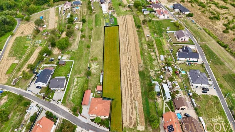 Na predaj investičný stavebný pozemok pre 3 RD, Trenč.Jastrabie - Letecký pohľad na pozemky v Trenčianskom Jastrabí s rodinnými domami a cestnou infraštruktúrou.