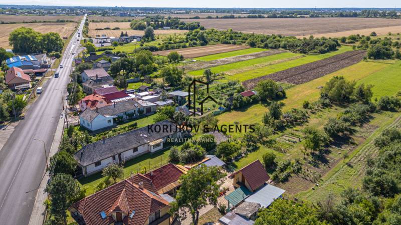 PREDAJ, Pozemok s rodinným domom Sečovce, okres Trebišov - Letecký pohľad na pozemky na bývanie v Sečovciach, cesta, domy a polia v okolí.