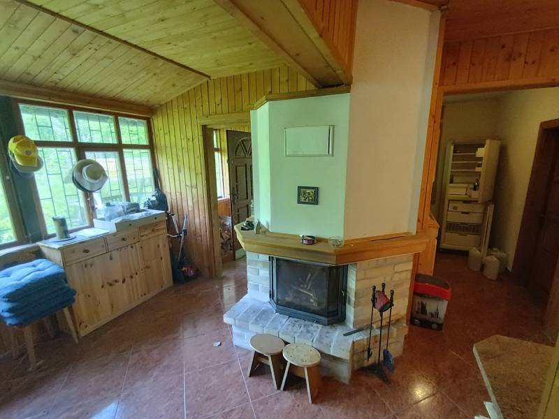 Na predaj chata pri jazere v Sklených Tepliciach - Interiér drevenej chaty so starším krbom a výhľadom na Sklené Teplice na ulici.