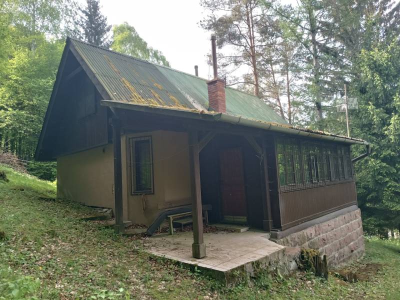 Na predaj chata pri jazere v Sklených Tepliciach - Chata na ulici Sklené Teplice, obklopená lesom, vidno strechu a verandu.