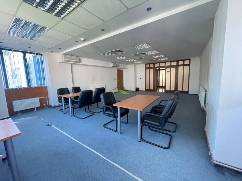 Zrekonštruované Kancelárie v centre mesta - na prízemí, aj na poschodí - Kancelárie s konferenčným stolom, stoličkami a veľkým oknom, podlaha pokrytá kobercom.