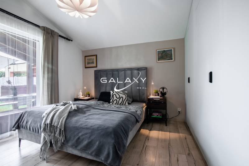 LUKRATÍVNY Moderný 3-izbový dom s bazénom – Čierna Voda, okres Galanta - Spálňa v rodinnom dome s posteľou, nočnými stolíkmi a lampami, s výhľadom von.