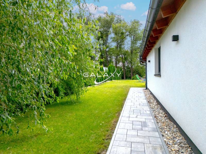 LUKRATÍVNY Moderný 3-izbový dom s bazénom – Čierna Voda, okres Galanta - Rodinný dom v Čiernej Vode s udržiavanou záhradou a chodníkom popri budove.