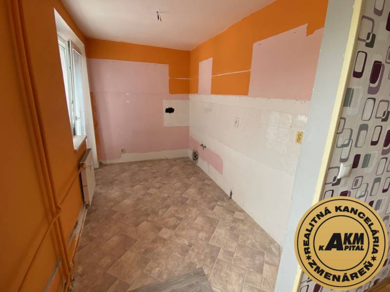 3 izbový byt na predaj,  80 m2, Zvolen - Podborová - Prázdna kuchyňa v 3-izbovom byte s oranžovo-ružovými stenami a vinylovou podlahou.