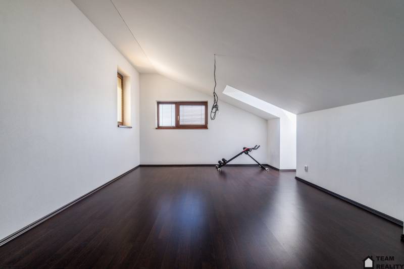 Moderný 4-izbový rodinný dom v Kittsee - Podkrovná miestnosť v rodinnom dome s cvičebným zariadením na tmavej podlahe.