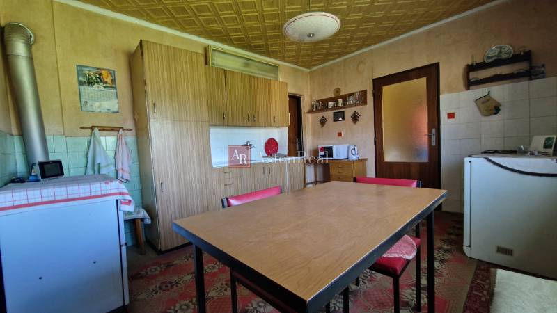 AstonReal: predaj rodinný dom v obci Mníšek nad Hnilcom - Kuchyňa v rodinnom dome s dreveným stolom, skrinkami a spotrebičmi.