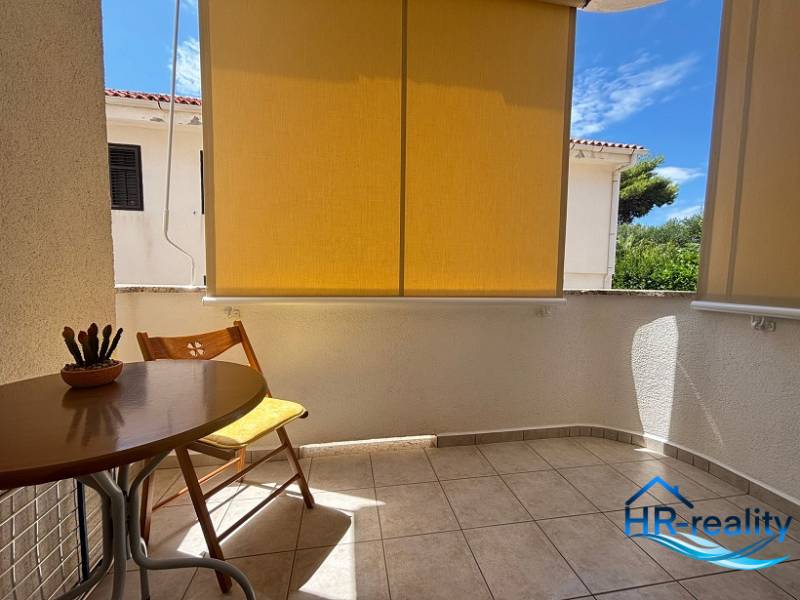 ☀NOVALJA (HR) -  2-izbový apartmán 45 m2 s terasou v 2.rade u mora - Balkón 2-izbového bytu v Novalji s dreveným stolom a zeleným výhľadom.