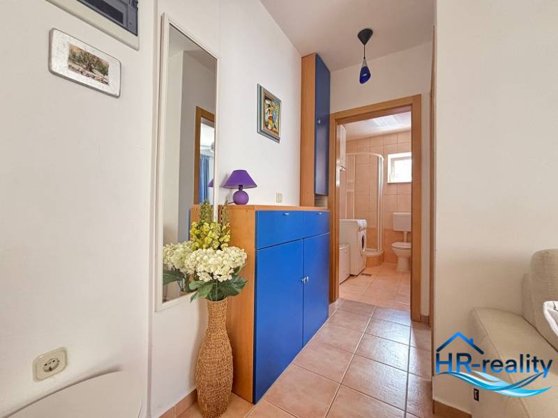☀NOVALJA (HR) -  2-izbový apartmán 45 m2 s terasou v 2.rade u mora - Chodba v 2-izbovom byte so vstupom do kúpeľne, modrým nábytkom a ozdobnými kvetmi.