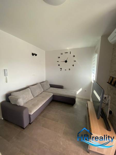 ☀NOVALJA (HR) - apartmán s pekným výhľadom na more  - Obývačka v 2-izbovom byte s pohovkou, televízorom a nástennými hodinami.