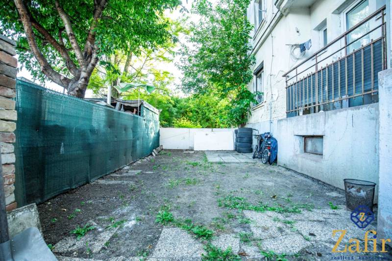 3 IZBOVÝ BYT 89,14 m2 VHODNÝ NA REKONŠTRUKCIU, ALE OBÝVATEĽNÝ UŽ TERAZ - Dvor pri 3-izbovom byte na Nobelovej ulici v Trnave s bicyklom a stromami.