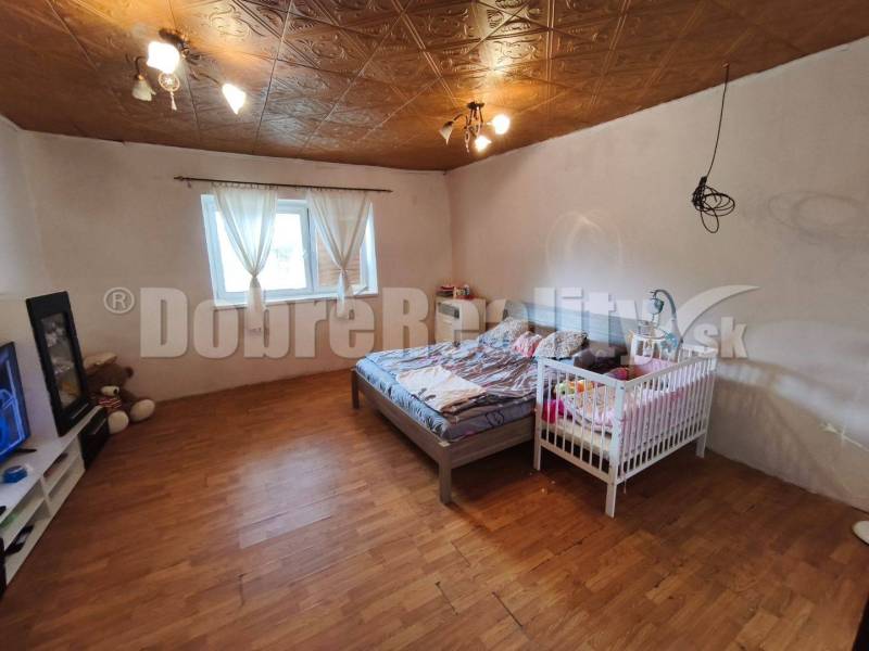 Rodinný dom v pôvodnom stave ,vhodný na rekonštrukciu....vo vyhľadávan - Spálňa v rodinnom dome s posteľou, detskou postieľkou a drevenou podlahou.