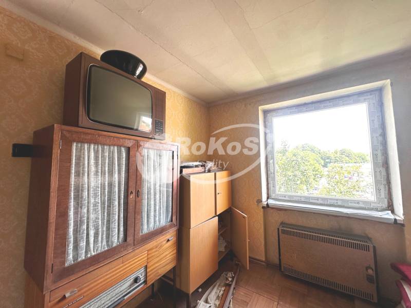 PREDAJ 3 izbový byt, Jarná ulica - Vintage nábytok a televízor v 3-izbovom byte s výhľadom cez okno.