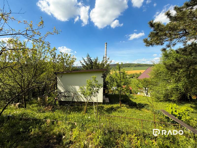 Na predaj záhrada, Trenčín-Chrasť - Záhrady v Trenčíne so zeleňou, domčekom a výhľadom na pole a lesy.