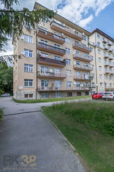 Priestranný 3 a pol izbový byt v Novom Smokovci - Bytový dom vo Vysokých Tatrách s balkónmi a parkoviskom pred budovou.