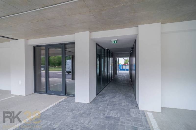  Na predaj – obchodné priestory v projekte Baťove rezidencie, Svit - Obchodné priestory v Svite so sklenenými dverami a dláždenou podlahou vedľa parkoviska.