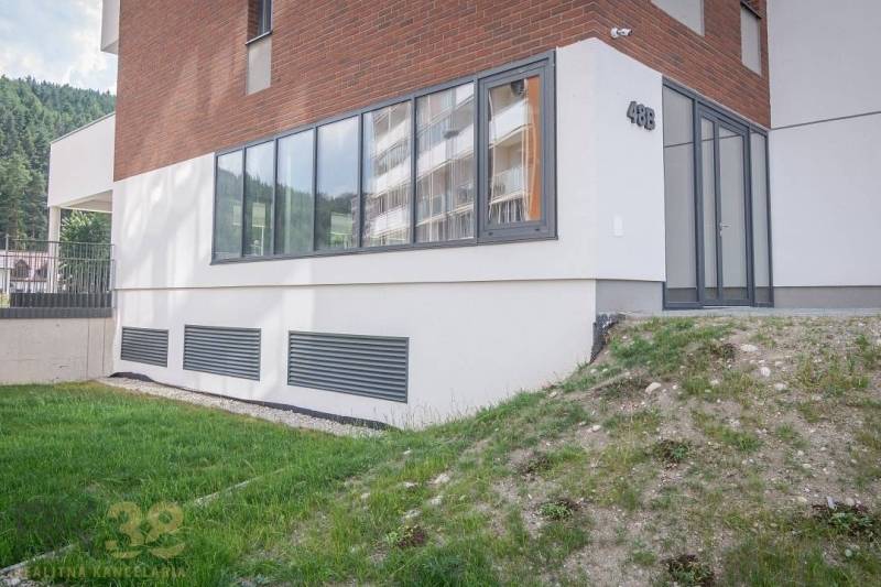 Na predaj – priestranné obchodné priestory v projekte Baťove rezidenci - Fasáda obchodných priestorov v meste Svit s veľkými oknami a zeleným trávnikom.