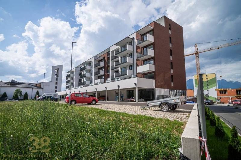 Na predaj – priestranné obchodné priestory v projekte Baťove rezidenci - Budova v meste Svit s obchodnými priestormi a parkoviskom v popredí.