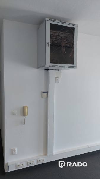 Prenájom kancelárie 70 m2 - Nám. sv. Anny, Trenčín - Kancelárie s komunikačným zariadením a sieťovým rozvádzačom na bielej stene.