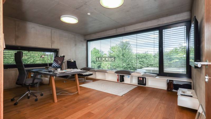NADŠTANDARDNÝ 6i RD s bazénom, pozemok 1583 m2, BA V.-Rusovce - Pracovňa v rodinnom dome s veľkým oknom a drevenou podlahou, moderný nábytok, výhľad na stromy.