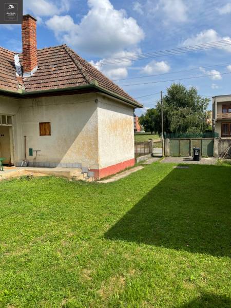 Ponúkame na predaj starší rodinný domček v Trenčianskych Stankovciach - Rodinný dom v Trenčianskych Stankovciach s trávnatým pozemkom a tehlovou strechou.