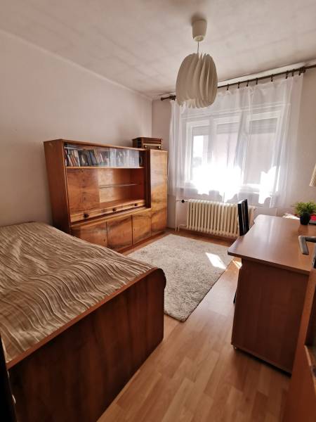5 izbový rodinný dom Topoľčianky - Izba v rodinnom dome s dreveným nábytkom, posteľou a koberečkom.