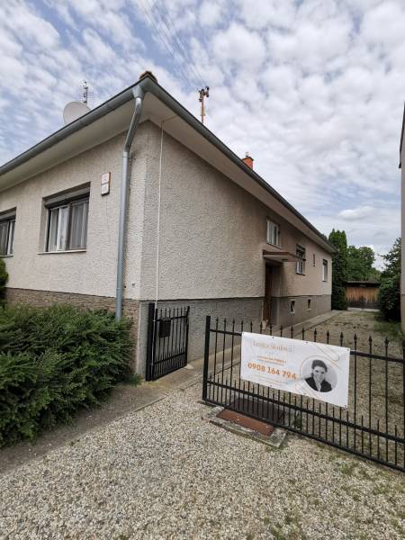 5 izbový rodinný dom Topoľčianky - Rodinný dom v Topoľčiankach s vchodom a bránou na kamenistej ceste.