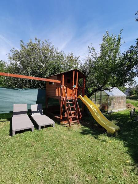 5 izbový rodinný dom Topoľčianky - Záhrada rodinného domu v Topoľčiankach s detským domčekom, šmykľavkou a ležadlami.