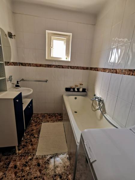 5 izbový rodinný dom Topoľčianky - Kúpeľňa v rodinnom dome so vstavanou vaňou a umývadlom, obložená svetlými obkladačkami.