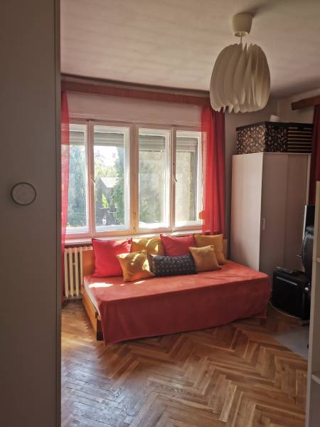 5 izbový rodinný dom Topoľčianky - Slnečná izba v rodinnom dome s oranžovým gaučom, vankúšmi a drevenou podlahou.