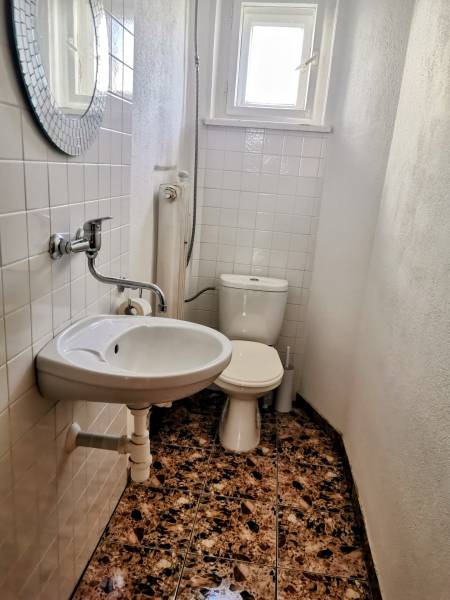 5 izbový rodinný dom Topoľčianky - Kúpeľňa v rodinnom dome s umývadlom, toaletou a oknom, biela dlažba na stenách.