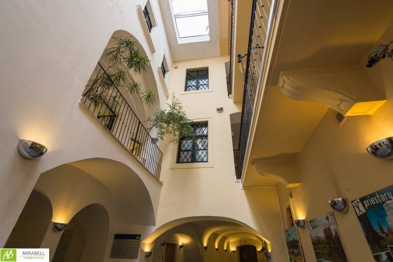 Klimatizované kancelárie v centre mesta na Michalskej ulici  - Interiér kancelárie s preskleným stropom, balkónmi a rastlinami.